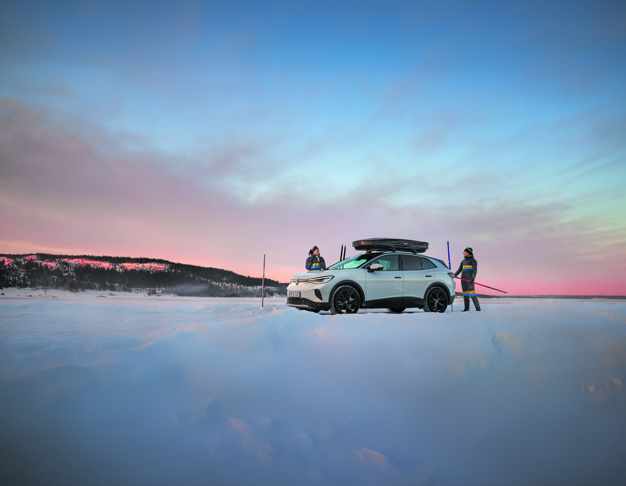 volkswagen id.4 gtx edition parkerad på ett snötäckt fjäll med en blå och rosa himmel i bakgrunden